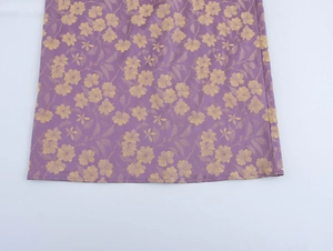 Close-up of purple jacquard dress fabric with yellow floral patterns and fine stitching detail