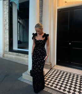 Detail of elegant black lace dress featuring delicate ribbon bow straps on the shoulder