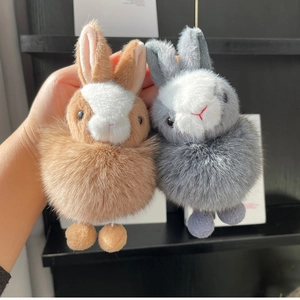 Close-up of fluffy bunny pom-pom keychains in brown and grey with soft long ears