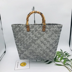 Detail of woven tote bag featuring natural bamboo handles and gray checkered pattern
