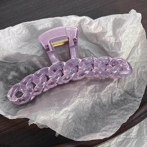 Close-up of translucent purple chain style hair claw clip on white textured paper
