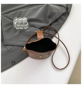 Macro view of minimalist brown leather bucket bag with vintage metal magnetic buckle detail