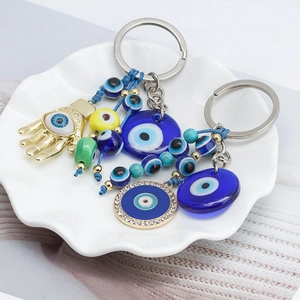 Detail of Evil Eye and Hamsa keychains with colorful beads in a white ceramic dish