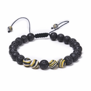 Détail de perles de lave 8mm et pierres rayées sur un bracelet tissé ajustable