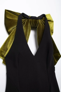 Détail d'une robe noire à col en V avec un grand nœud en velours vert olive au cou