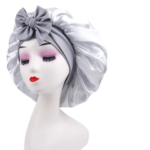 Detail of silver satin sleep cap with large bow knot and pleated glossy fabric texture