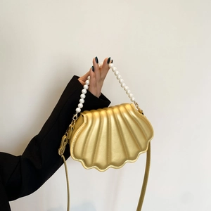 Golden shell-shaped crossbody bag with pearl handle and slim gold shoulder strap