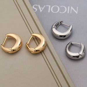 Minimalist crescent hoop earrings in gold and silver finish on a book background