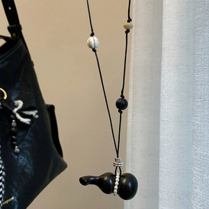 Detail of wooden gourd pendant with pearl inlay on a black adjustable waxed cord