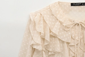 Detailed view of beige chiffon shirt with layered ruffles and polka dot jacquard texture