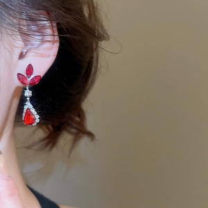 Close-up of red gemstone and diamond floral earrings worn by a model in royal court style