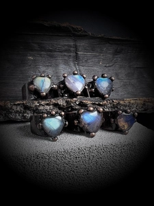 Macro detail of six vintage heart-shaped moonstone rings with aged bronze solder plating