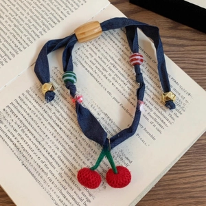 Detail of fabric scrunchie with crochet cherries and mixed beads on vintage book