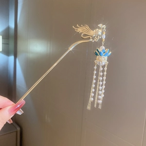 Détail d'un pic à cheveux phénix doré avec pompons en perles et accents de lotus bleu