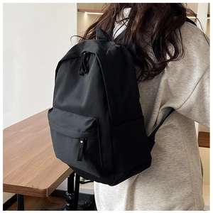 Side view of a minimalist large capacity black nylon backpack worn by a model