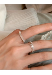 Detailed view of silver bow ring and lace band with mini pearls on model finger