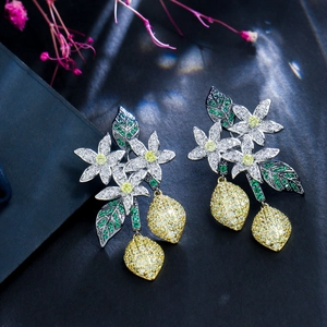 Detailed shot of floral lemon earrings with zircon stones on a dark reflective surface