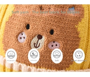 Close-up of ginger yellow dinosaur baby knit hat showing soft texture and bear pattern