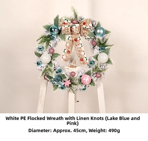 Detail of flocked Christmas wreath with burlap bow, blue and pink ornaments on white easel