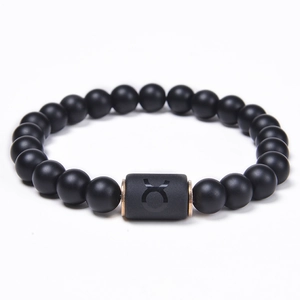 Detail of matte black onyx Taurus zodiac bracelet with copper-tone metallic charm