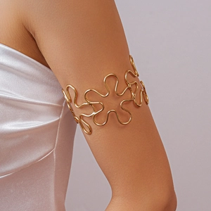 Detailed view of an elegant golden hollowed floral wave armlet on a model arm