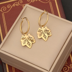 Gold leaf pendant earrings on a jewelry box with a vintage book background
