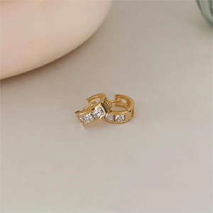 Macro view of gold-plated hoop earrings with square-cut cubic zirconia in claw setting