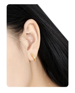 Close-up of golden geometric S925 sterling silver hoop earrings with vertical texture