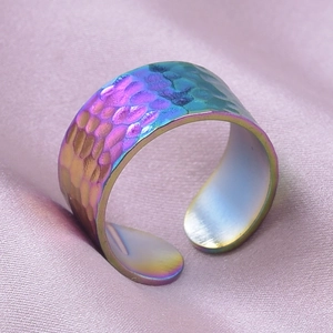 Macro detail of rainbow stainless steel ring with hammered texture on purple silk