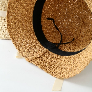 Détail d'un chapeau de paille avec cordon de serrage réglable et bandeau noir