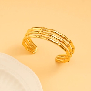 Close-up of golden 18K gold-plated stainless steel open cuff with triple bamboo texture