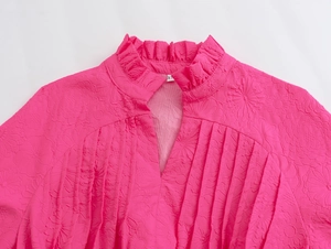 Close-up of rose pink blouse with ruffled collar and 3D floral jacquard texture