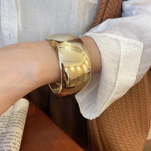 Polished gold wide open bangle bracelet shown on model with minimalist style