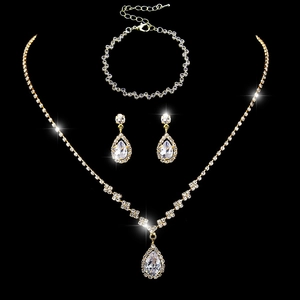 Three-piece gold jewelry set with teardrop crystals on a black background