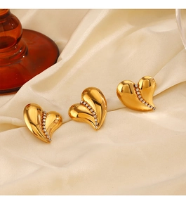 Close-up of 18K gold plated heart earrings with small crystals on beige silk