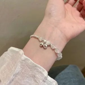 Dettaglio di un bracciale in perline d'argento con opali e piccoli ciondoli delicati