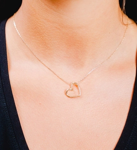 Close-up of minimalist gold-plated hollow heart pendant necklace on woman's neck