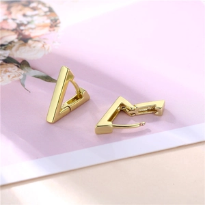Polished 18K gold geometric triangle huggie earrings on a floral decorative background