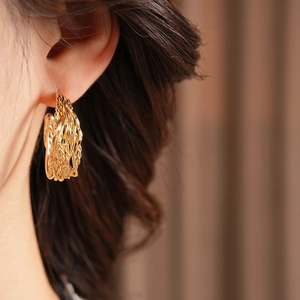 Close-up of 18K gold plated twisted C-shape hoop earrings worn by a model