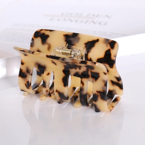 Macro view of a large tortoise shell hair claw clip with a glossy finish and gold spring