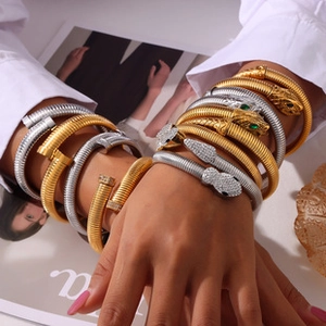 Dettaglio di bracciali sovrapposti oro e argento con design a serpente e chiodo su modella