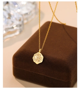 Macro detail of a gold s925 silver coin necklace with tic-tac-toe zircon engraving