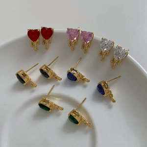 Golden heart-shaped stud earring set with multi-color rhinestones in a ceramic dish