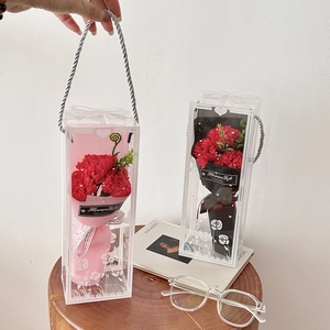 Close-up of red soap flower bouquets in transparent gift boxes with carry handles