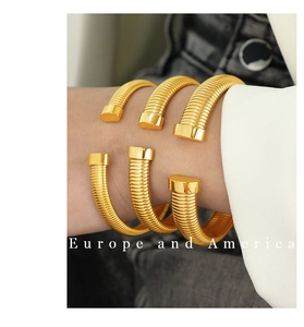 Close-up of three stacked gold spiral bangles featuring a vertical striped texture