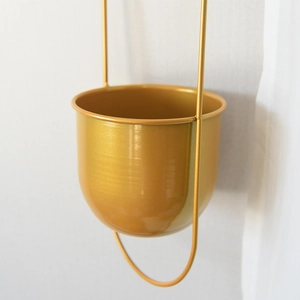 Detail of hanging gold metal flower pot with minimalist U-shaped hanger and round base