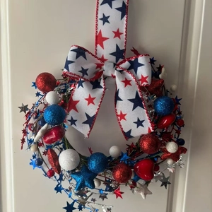 Patriotic July 4th wreath with red white and blue stars on a white wooden door background