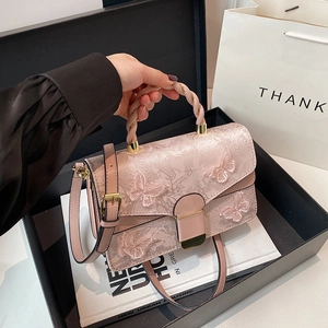 Pink crossbody bag with butterfly embroidery and twist handle in a gift box setting