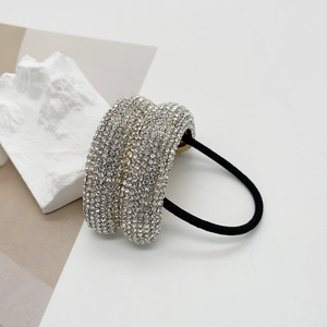 Close-up of a wide alloy hair tie with sparkling rhinestones on a black elastic band