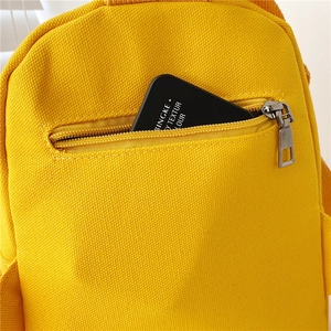 Detail of yellow canvas backpack showing zipper pocket and durable stitching texture